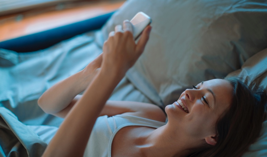 woman looking at phone while in bed