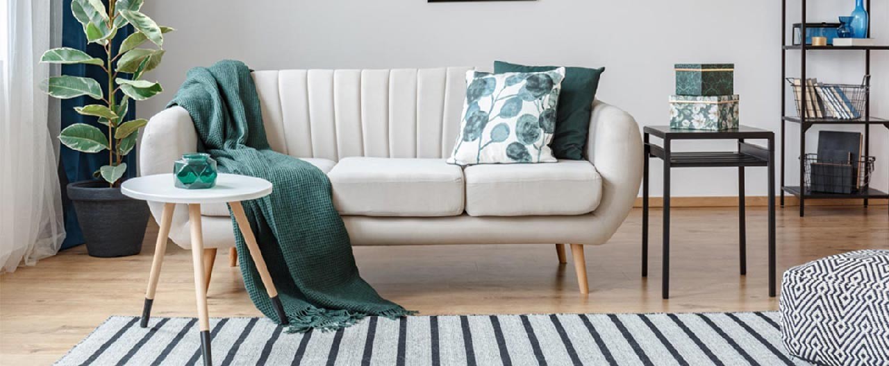 white sofa with green blanket and cushions