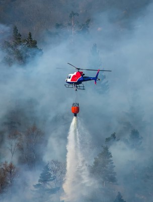 helicopter dropping water on wildfire