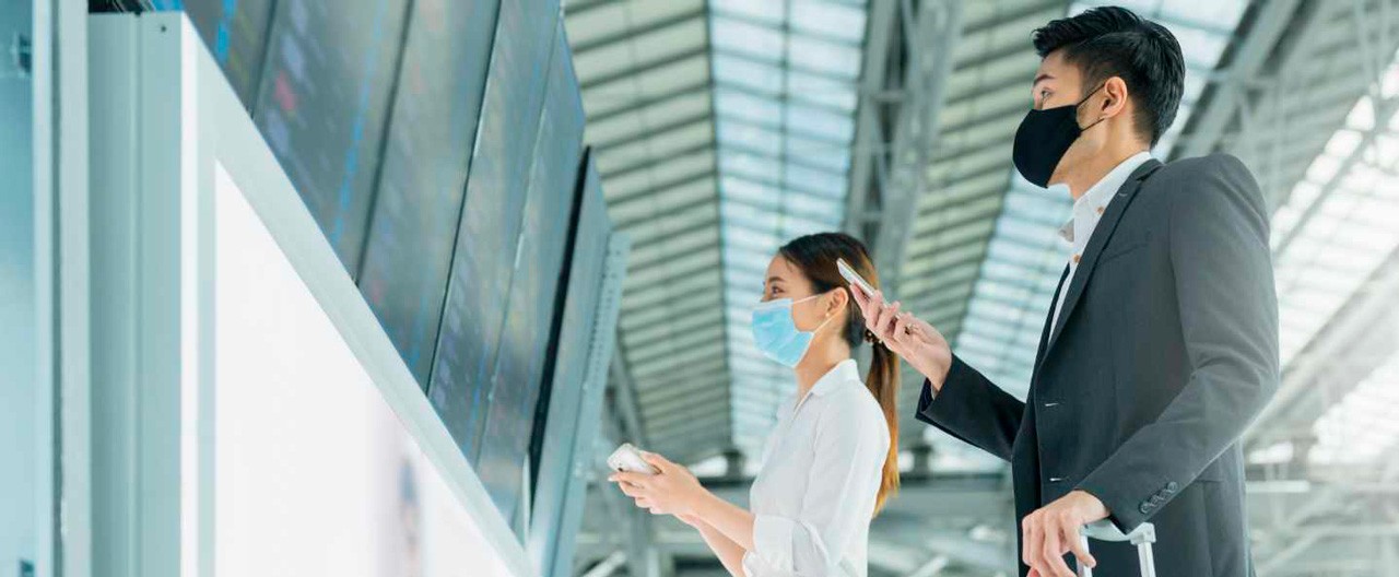 safe travel woman man looking at flight schedule board