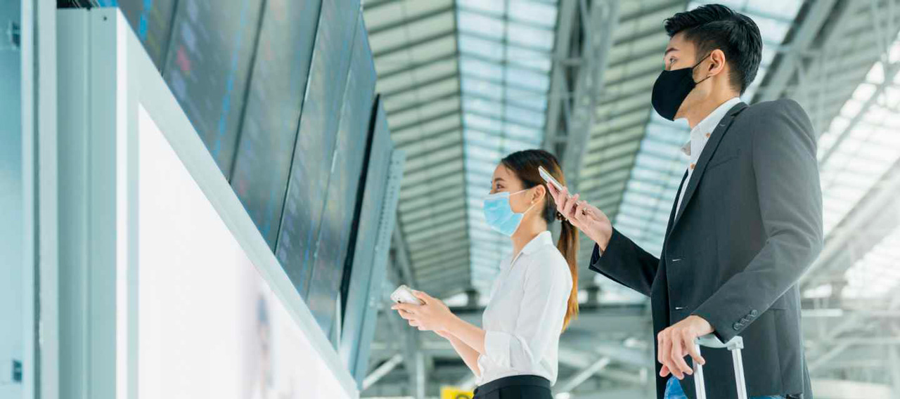 safe travel woman man looking at flight schedule board