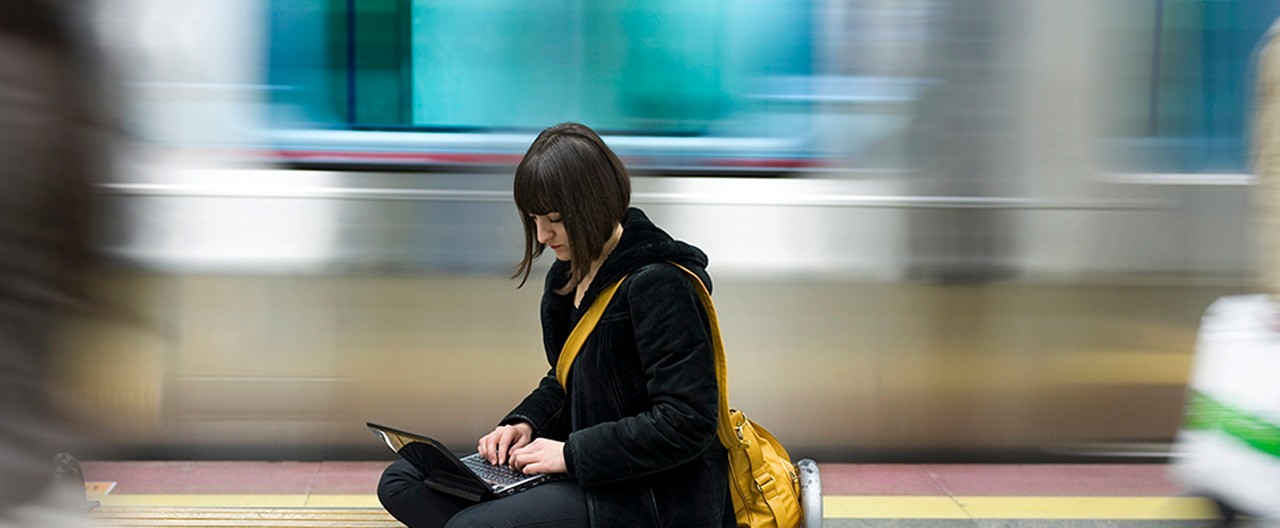woman on laptop at subway station