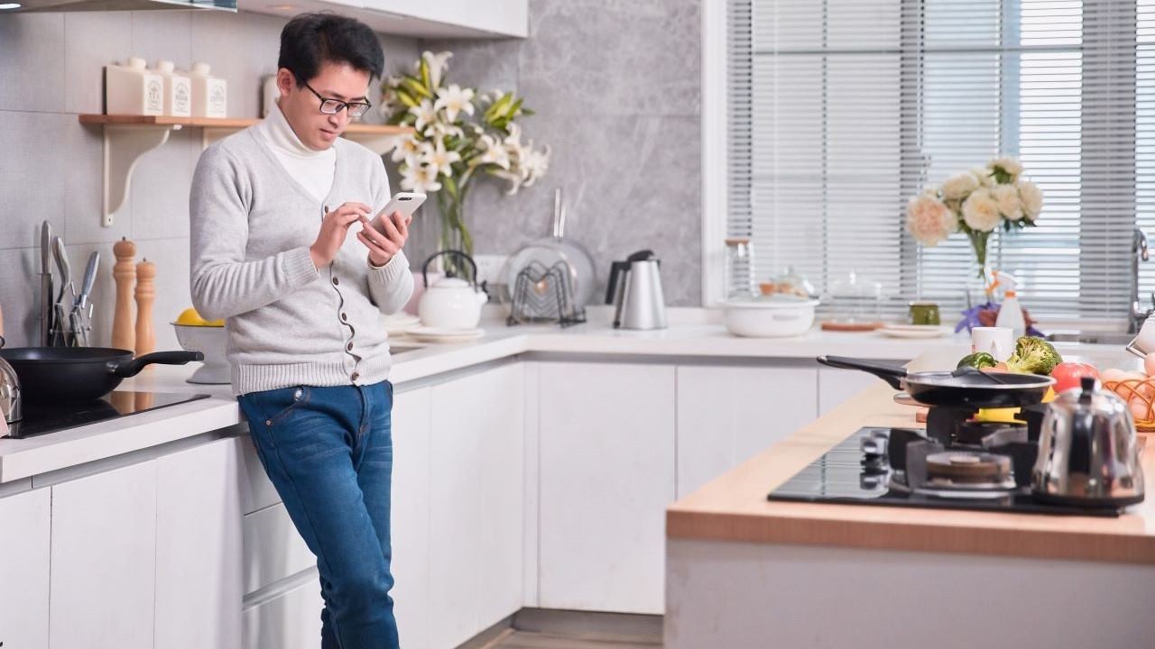 man texting in kitchen