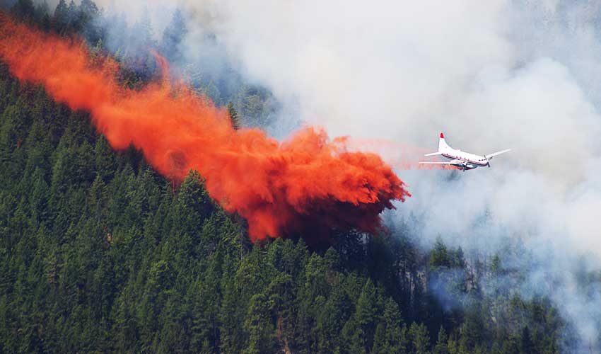 A plane flying above a wildfire