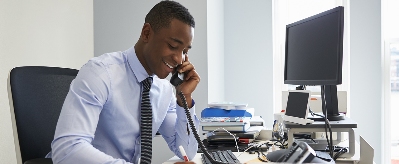 man jotting down notes while on the phone
