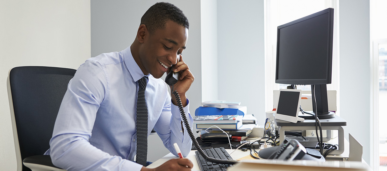 man jotting down notes while on the phone