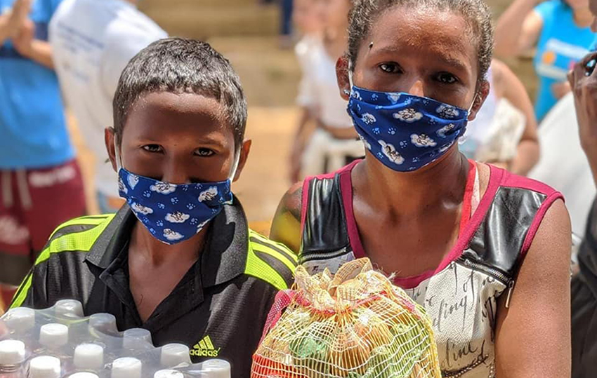 niños con máscaras portando suministros de alimentos 