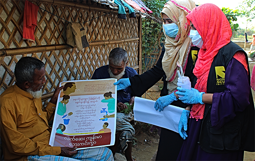 Umme Habiba, Rumana Afroz (wearing masks) and other IRC community health volunteers are trying to reach as many people as they can in the Cox’s Bazar refugee camp with information about how they can protect themselves from COVID-19.