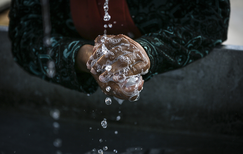 A woman cleans her hands at a refugee camp in northern Greece.