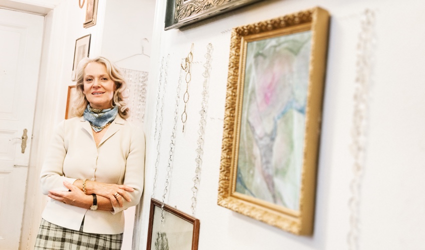 An older woman posing by her valuable artwork