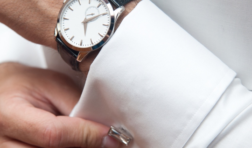 A man fixing his cufflink with a valuable watch on his wrist