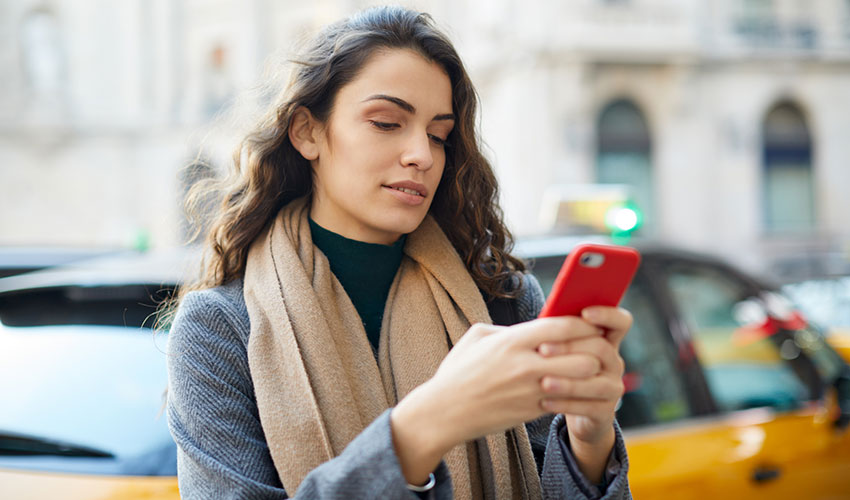 woman texting on city sidewalk