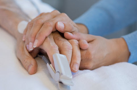 hands clasped at medical facilty bedside