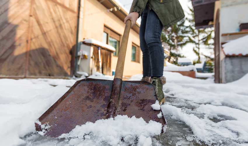 A woman shoveling snow from a walkway