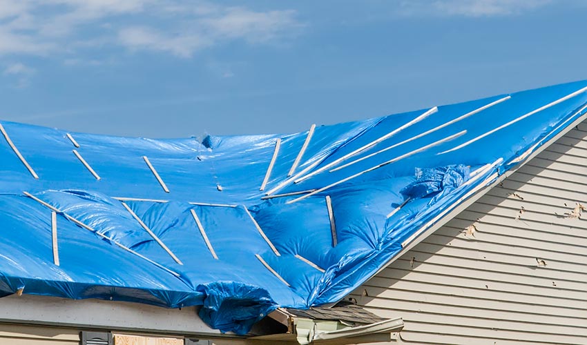A damaged roof covered in tarp
