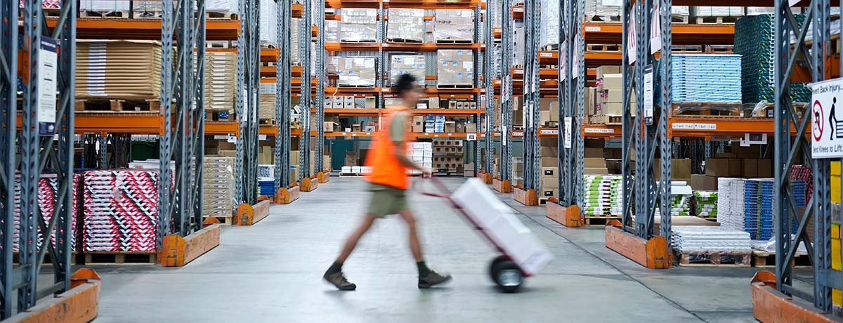 man pushing dolly in warehouse