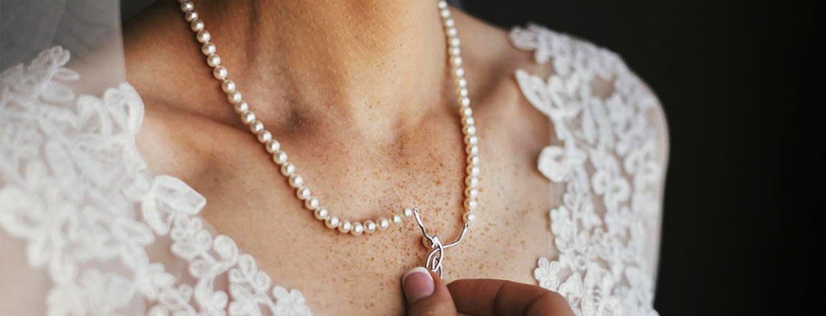 a woman touching her pearl necklace