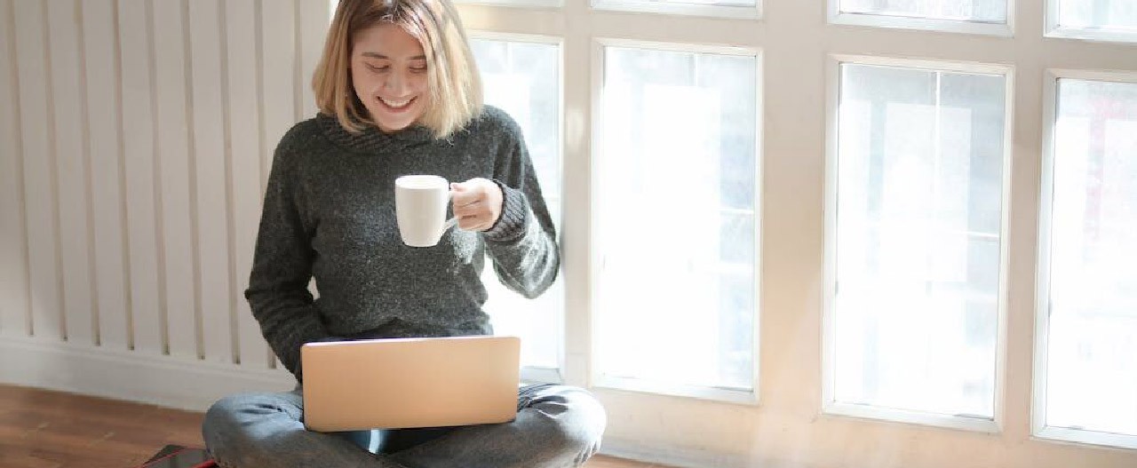 female holding mug laptop