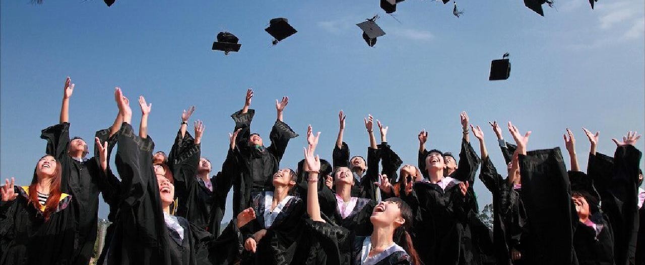graduates throwing mortarboard cap high