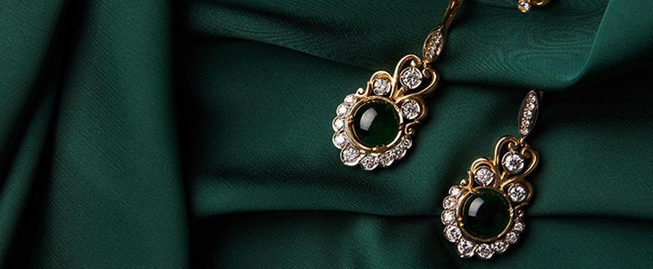 emerald earrings on green cloth