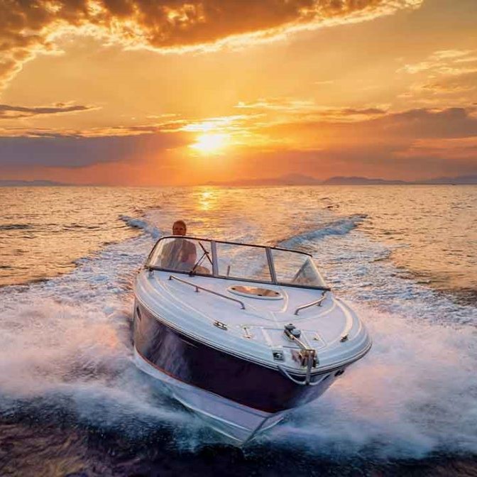 boat racing across water at sunset